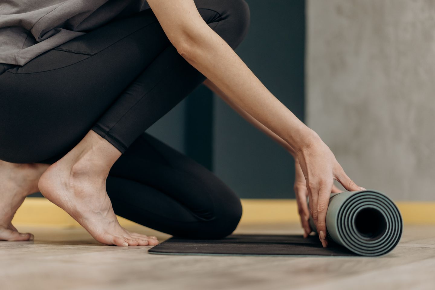 A woman rolling out a yoga mat for an indoor fitness routine, emphasizing calmness and focus.